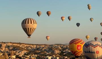 Hot air balloons floating over a rocky landscape during the day.