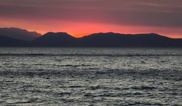 Ocean view with a dramatic sunset over distant mountains.