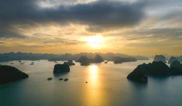 Sunset over Halong Bay with silhouetted karst islands.