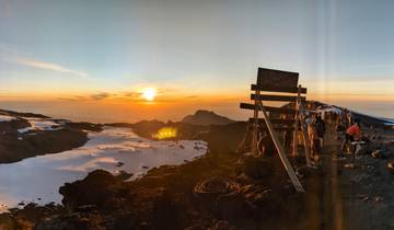 People gathered at a mountain summit at sunrise.
