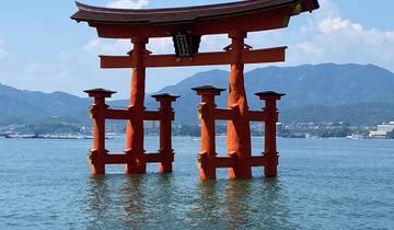 Large orange torii gate standing in the water.