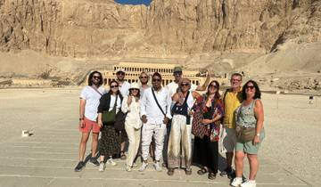 Group standing in front of an ancient temple carved into a cliff.