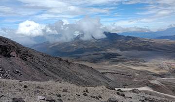 A vast landscape with rocky terrain and clouds over a mountain.
