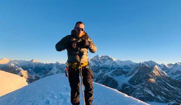 Person climbing a snowy mountain with panoramic views.