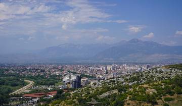Cityscape with mountains in the background under a clear sky.