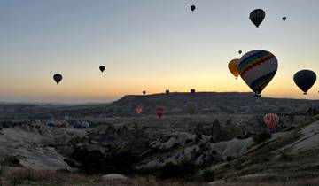 Hot air balloons over a valley during sunrise.