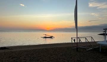 Sunset view of a beach with a small boat in the water.