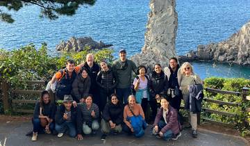 Group photo by the sea with a rocky island in the background.