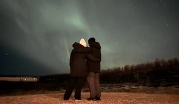 Two people embracing under the Northern Lights.