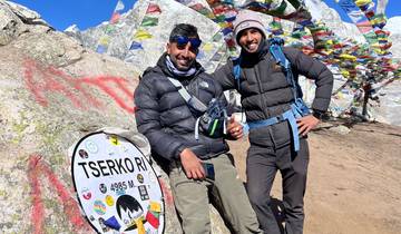 Two hikers standing beside a cairn with prayer flags.