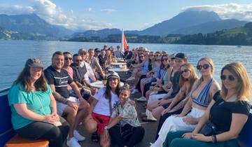 Group of people on a boat with scenic mountain and lake view.