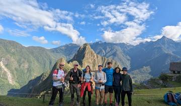 Group of hikers posing with Machu Picchu and mountains in the background.