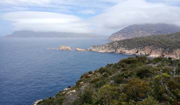 Mountain and ocean view with cloudy sky.