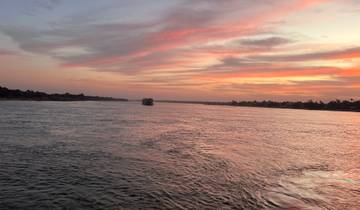 Sunset over a river with a boat in the distance.
