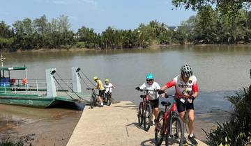 People with bicycles coming off a small ferry on a river.