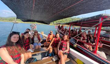 People on a boat wearing life jackets with a scenic view of water and greenery.