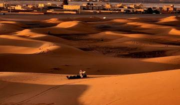 Desert dunes with a subtle orange glow at sunset.