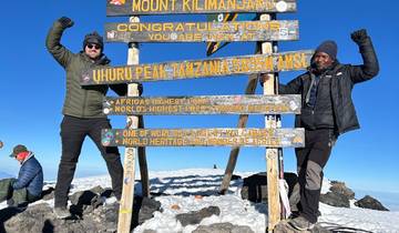 People at Uhuru Peak, Mount Kilimanjaro sign.