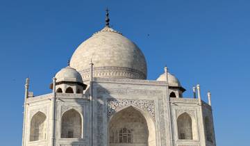 The iconic dome of the Taj Mahal against a clear blue sky.