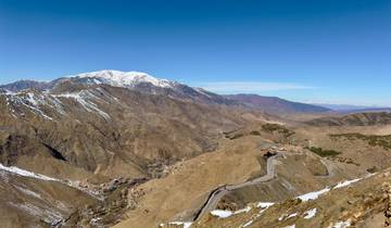 Mountain range with snow-capped peaks and winding road.