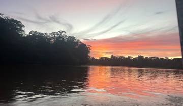 Sunset over a calm river with trees lining the banks.