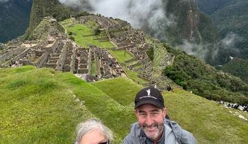 Couple smiling with Machu Picchu ruins in the background.