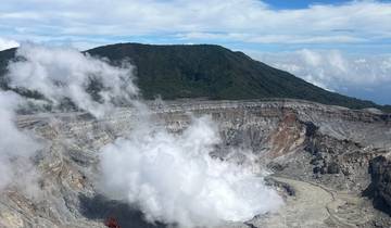 Steaming volcanic crater with lush mountains.