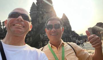 Two people smiling in front of an ancient temple.