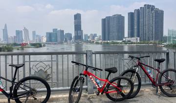 Bicycles parked in front of a river with a city skyline.