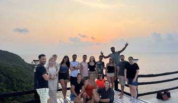 A group of people posing on a deck during sunset with the ocean in the background.