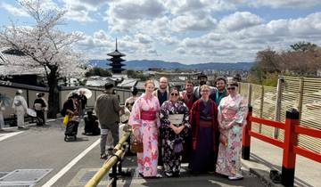 A group of people in traditional clothing with a pagoda in the background.