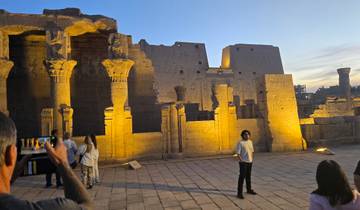 Tourists exploring an ancient Egyptian temple during sunset.