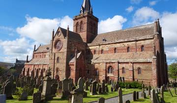 A large cathedral surrounded by a graveyard under a blue sky.