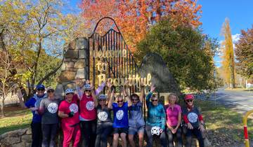 Group of cyclists posing under a 'Welcome to Beautiful Bright' sign.