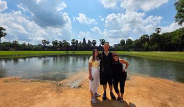 Smiling group posing with Angkor Wat temple in background.