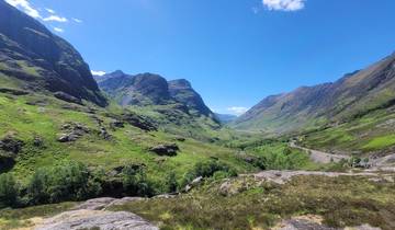 Scenic valley surrounded by steep mountains under a blue sky.