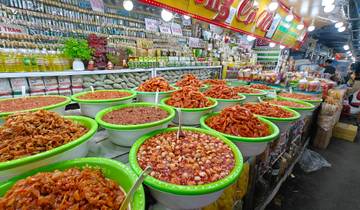 A bustling street market with a variety of food items in large bowls.
