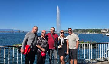 Group of people posing by a lakeside with a prominent fountain.