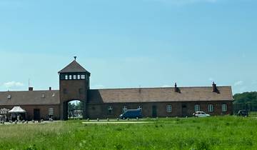 A brick entrance to a historical site with a tower.