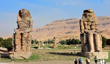 The Colossi of Memnon statues with tourists nearby.