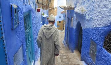 Person walking through the blue-painted streets of Chefchaouen.