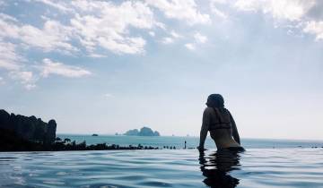 Person swimming in infinity pool overlooking the sea.