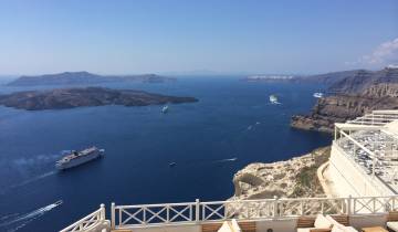 High view of blue sea with white cruise ships and islands.