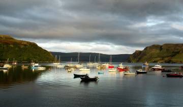 Boats anchored in a serene harbor surrounded by hills.