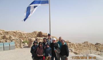 Group of people posing with the flag of Israel, outdoors on a clear day.