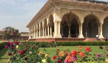 Historical palace with arches and a garden of flowers.