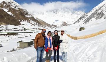 Family posing on a snowy path with mountainous terrain.