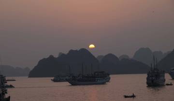 Boats sailing on a misty bay at sunset.