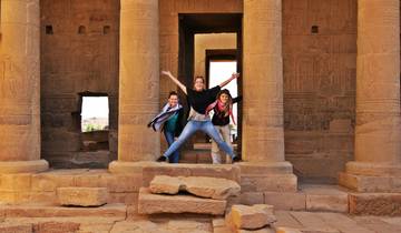 Three people playfully posing in front of ancient temple ruins.