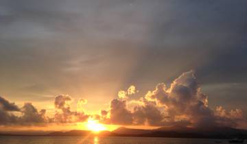 Dramatic sunset with clouds and mountain silhouette.